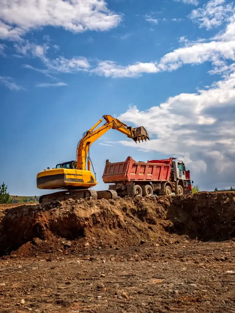Track excavator loading a dump truck during earthmoving
