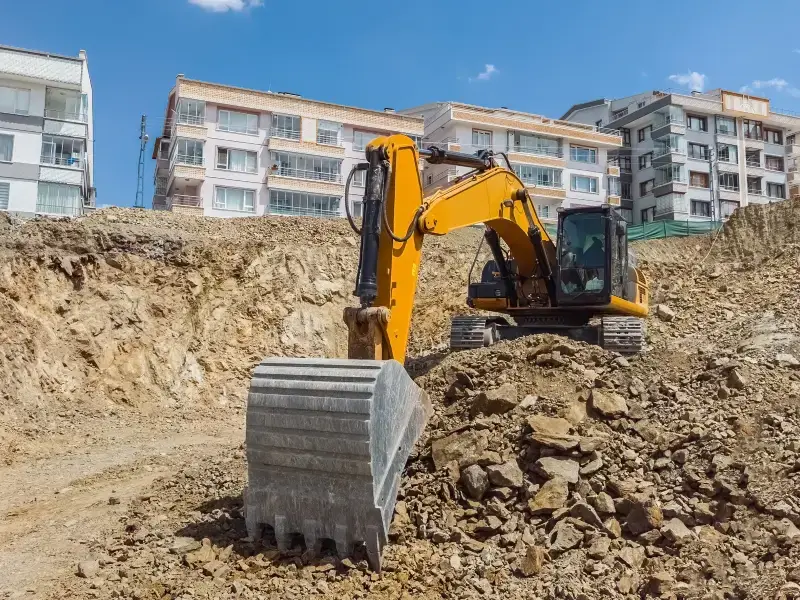 Track excavator making a deep cut in rocky soil