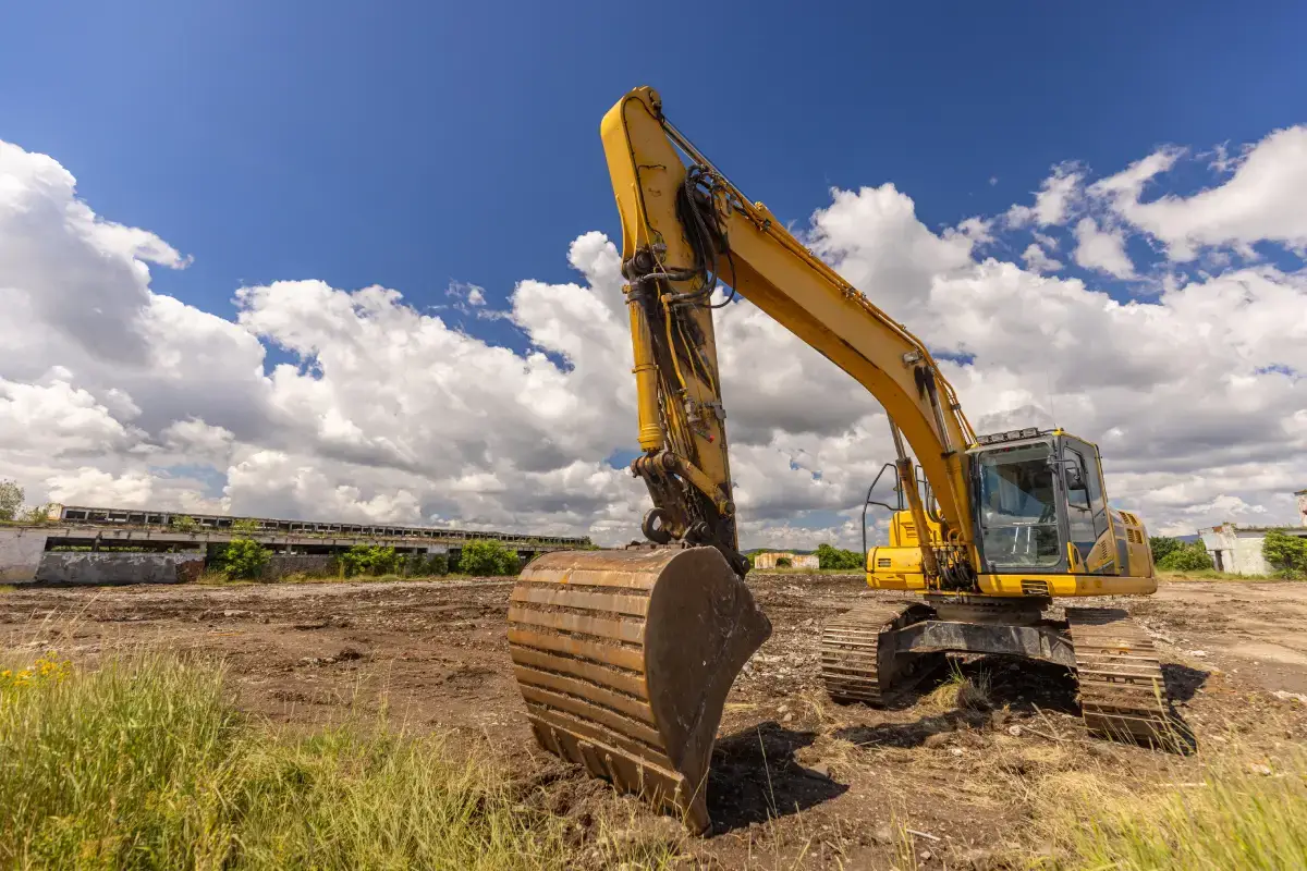 Excavator clearing, demolishing and grading a job site