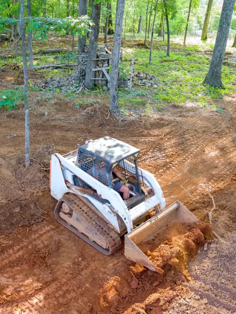 Track loader grading ground during land clearing